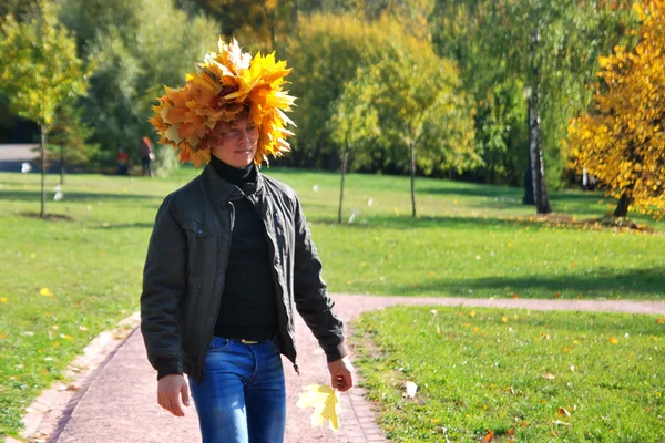 Niño con una corona de hojas de arce brillante en el parque de otoño — Foto de Stock