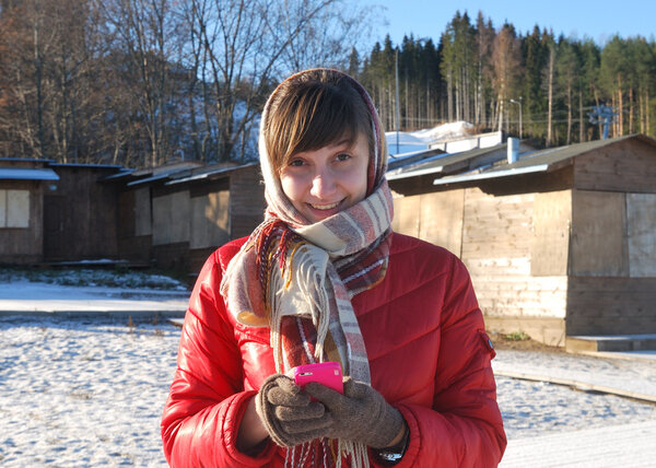 Улыбающаяся девушка в красной куртке с мобильным телефоном
