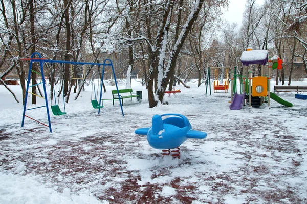 Parco giochi per bambini nel parco sotto la prima neve — Foto Stock