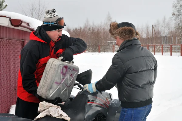 Dos chicos están preparados para ATV Extremo viaje de invierno, vierte gasolina —  Fotos de Stock