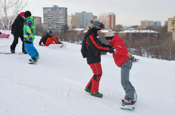 Jovem snowboarder e instrutor durante a descida da estância de esqui de montanha — Fotografia de Stock