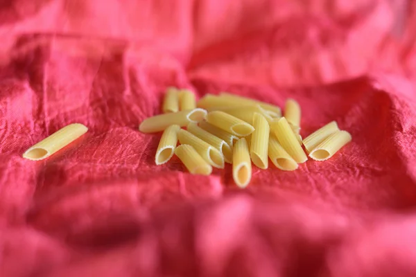 Gul pasta utspridda på bordet på en röd bakgrund — Stockfoto