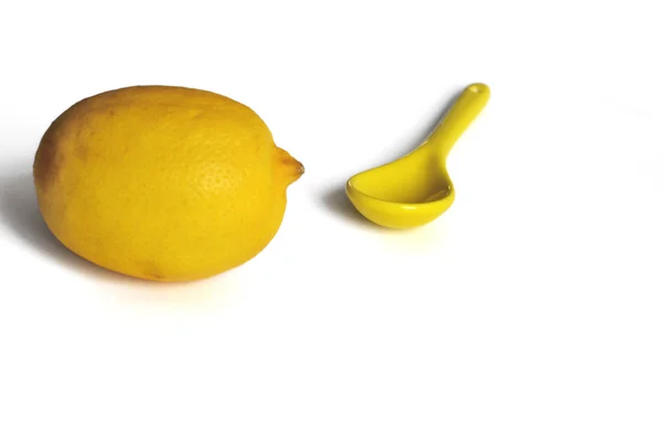 Yellow lemon and yellow spoon on a white background — Stock Photo, Image