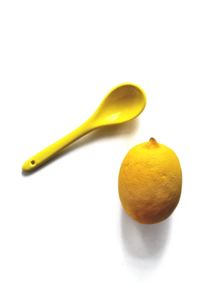 Yellow lemon and yellow spoon on a white background — Stock Photo, Image