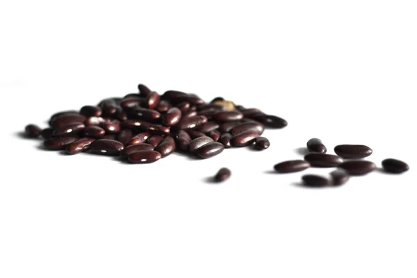 A handful of dark bean beans scattered on a table on a white background — Stock Photo, Image