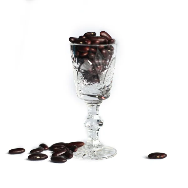 Crystal glass with black beans on a white background — Stock Photo, Image