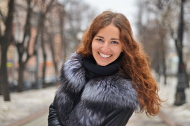 Kırmızı kıvırcık saçlı neşeli gülümseyen kız