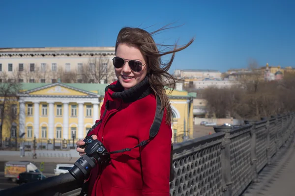 Girl with camera in sunglasses on the bridge — Stock Photo, Image