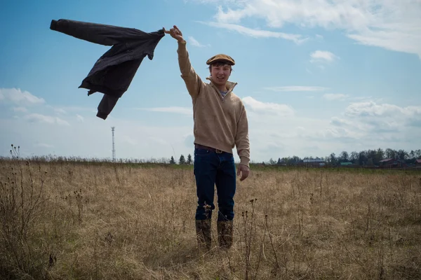 Un giovane uomo in un maglione marrone e cappello cammina sul campo — Foto Stock