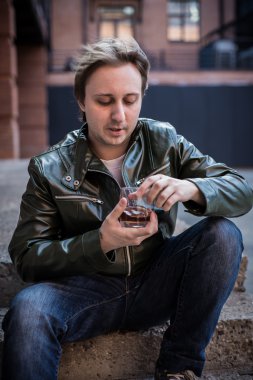 Bir bardak viski ile deri ceketli genç adam