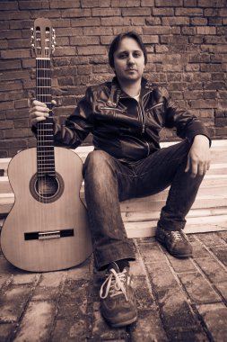 Bir gitar ile deri ceketli genç adam