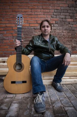 Bir gitar ile deri ceketli genç adam