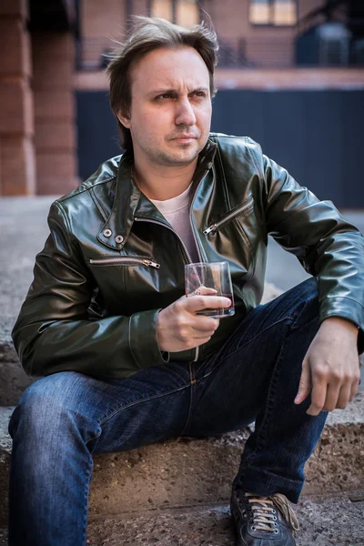 The young man in a leather jacket with a glass of whiskey — Stock Image The young man in a leather jacket with a glass of whiskey Royalty Free Stock Images