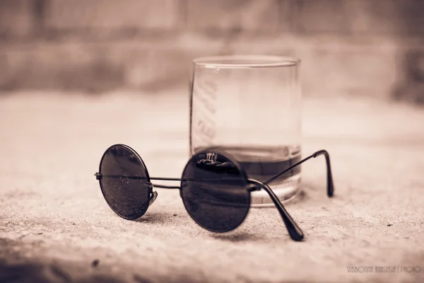 A glass of whiskey and black sunglasses — Stock Image A glass of whiskey and black sunglasses Royalty Free Stock Images