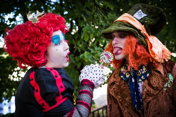 Jovem mulher e homem à imagem do Chapeleiro e da Rainha Vermelha do conto de fadas sobre Alice — Fotografia de Stock