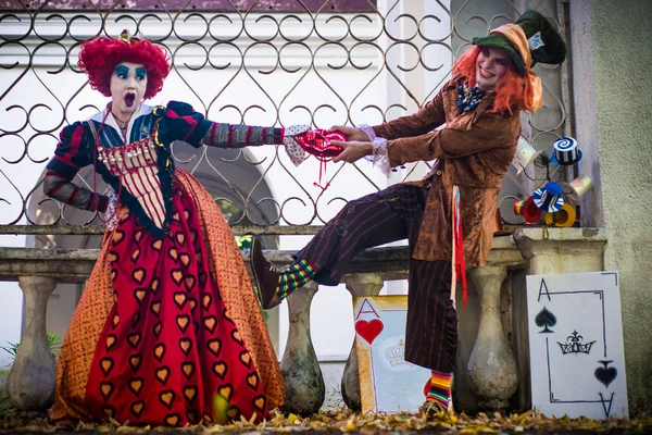 Jovem mulher e homem à imagem do Chapeleiro e da Rainha Vermelha do conto de fadas sobre Alice — Fotografia de Stock