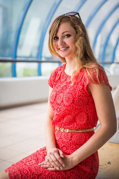 Menina em um vestido de coral sentou-se em um banco — Fotografia de Stock