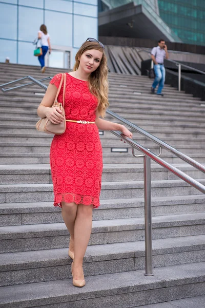 The girl in the dress of coral color descends the ladder business center — Stock Photo, Image
