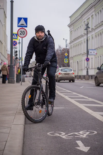 Un giovane uomo in bicicletta attraverso la città in autunno giorno — Foto Stock