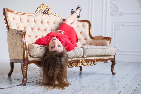 Ung smal kvinna med ljusa makeup poserar på en vacker soffa — Stockfoto