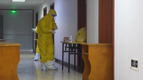 Çin 'deki COVID-19 salgını sırasında uluslararası gezginler otelde 14 gün karantina altında tutuldu. Koruyucu giysiler içindeki sağlık personeli boğaz temizliği yapıyor., — Stok video