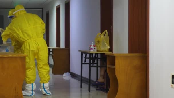 COVID-19期間中国で14日間にわたり隔離された外国人旅行者保護服を着た医療従事者は、入国管理官が住んでいるホテルで喉の綿棒サンプリングを取ります — ストック動画