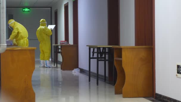 Během epidemie COVID-19 V Číně, mezinárodní cestující v karanténě 14-denní v hotelu.Zdravotnický personál v ochranných oblecích berou krční výtěry, — Stock video