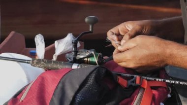 Kıyıda balık tutan bir adam. Balıkçılık yapmadan önce balıkçılık ekipmanları hazırlayın, olta ipi bağlayın ve yem asın.