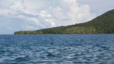 Dalgalar kıyıdaki kayaların üzerinden geçti. Mavi berrak su yüzeyi