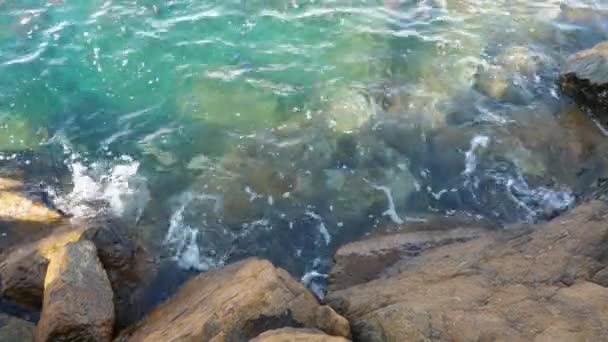 As ondas lavaram-se sobre as rochas na costa. Superfície de água clara azul Vídeo De Stock