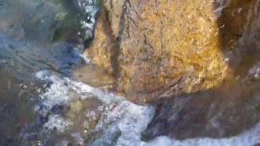 Dalgalar kıyıdaki kayaların üzerinden geçti. Mavi berrak su yüzeyi