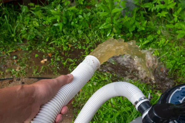 Backwash of a water filter, a hand holding a hose in the foreground