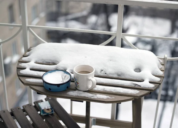 Abandoned ashtray and coffee mug on the snowy balcony, outdoor shallow DOF shot