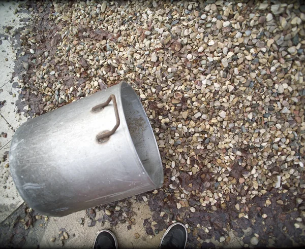 站在砾石堆旁边的人的脚和用来搬运的砂锅 — 图库照片