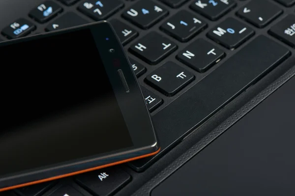 Smartphone on a keypad of laptop — Stock Photo, Image