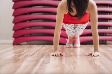 Genç ve güzel bir kadın yerde aletsiz egzersiz yapıyor. Tam boy portre.