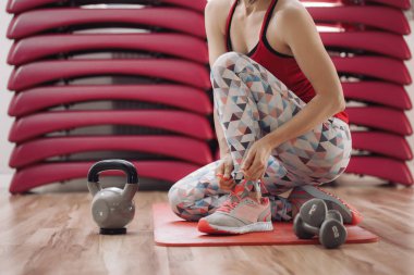 Güzel genç bayan spor salonunda egzersiz yapmaya hazırlanıyor.