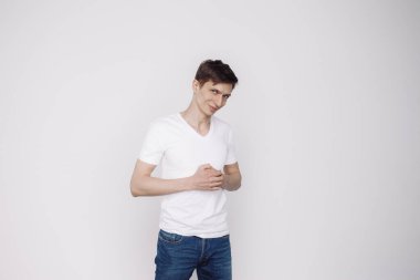 Beyaz arka planda izole edilmiş beyaz tişörtlü gülümseyen genç adam portresi.