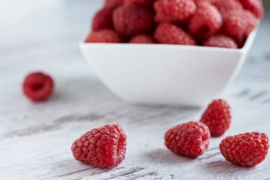 Olgun ahududu küçük kasede beyaz bir arka planda.