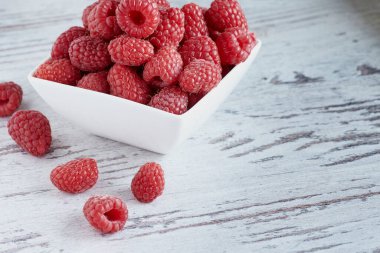 Olgun ahududu küçük kasede beyaz bir arka planda.