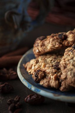 Mavi tabakta kurabiyeler, etrafa saçılmış baharatlar. Arka plan karanlık.