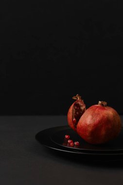 Siyah arkaplanda siyah bir çanakta nar.