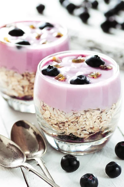 İki yabanmersinli yoğurt, beyaz ahşap masada çay kaşığı