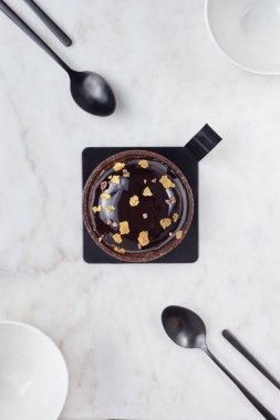 Çikolatalı pasta, iki beyaz kase ve dört tatlı kaşığı beyaz mermer tahtada.