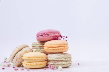 Beyaz arka planda birkaç renkli badem kurabiyesi ve çiçek.