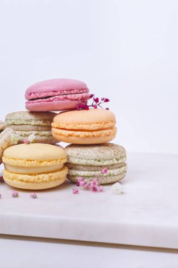 Beyaz arka planda birkaç renkli badem kurabiyesi ve çiçek.