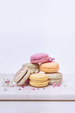 Beyaz arka planda birkaç renkli badem kurabiyesi ve çiçek.