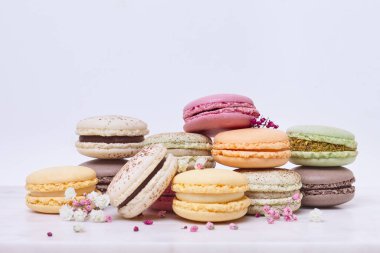 Beyaz arka planda birkaç renkli badem kurabiyesi ve çiçek.