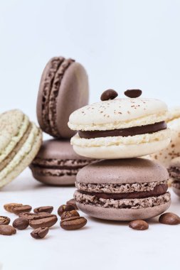 Beyaz arka planda birkaç renkli makaron ve kahve çekirdeği.