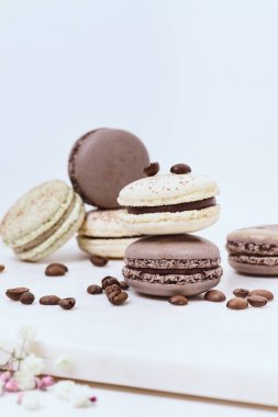 Beyaz arka planda birkaç renkli makaron ve kahve çekirdeği.